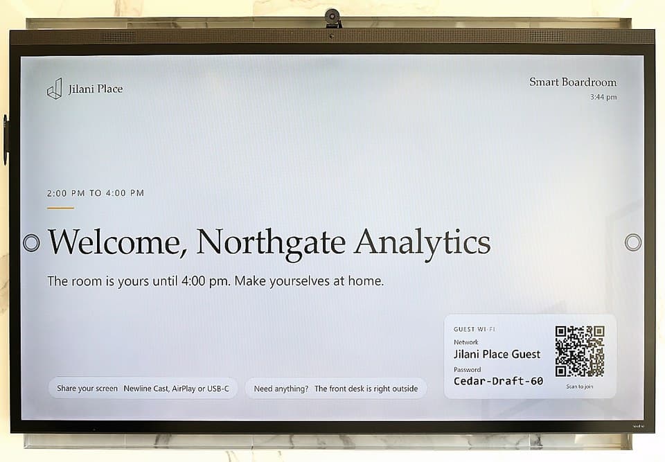 The Smart Boardroom screen welcoming a company by name, with the guest Wi-Fi shown